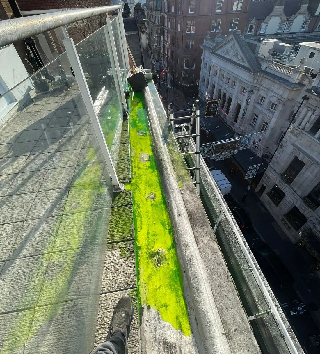Green dye in a roof-terrace gutter above a central London street, used to trace a leak