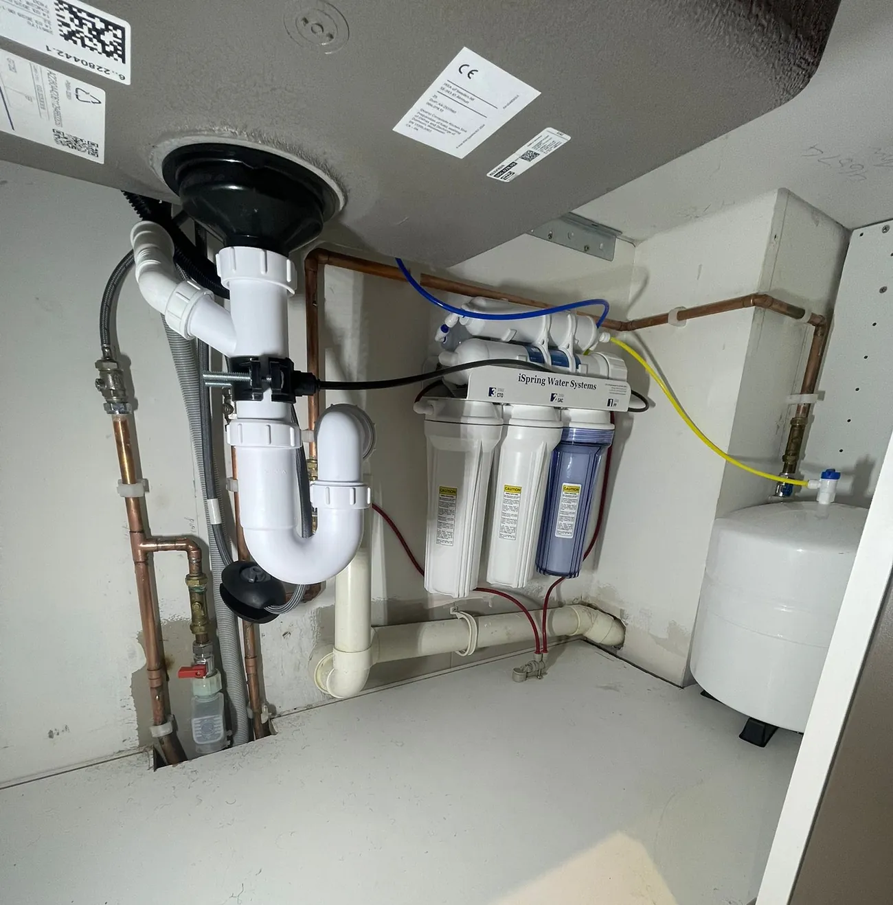 Neat under-sink plumbing with new waste pipes, valves and a water filter